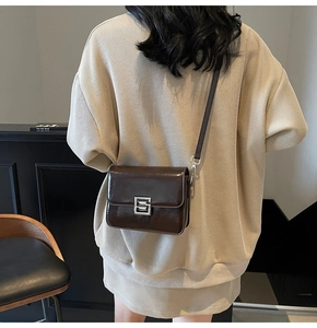 Close-up of shiny brown patent leather bag with square silver metal lock and leather strap