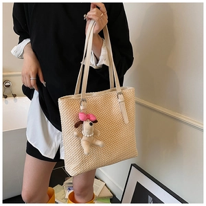 Detail of cream woven tote bag featuring a cute puppy charm and adjustable shoulder strap