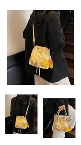 Detail of yellow drawstring bucket bag with side pockets and a colorful elephant charm