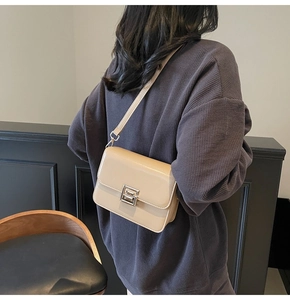 Detailed view of beige flap crossbody bag with silver geometric buckle on a model