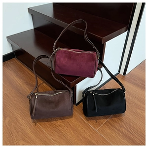 Detailed texture of suede cylinder shoulder bags in burgundy, black and brown colors