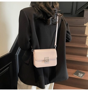 Detail of dusty pink leather crossbody bag with silver buckle on a wooden staircase