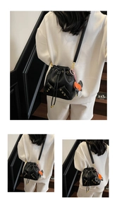 Detail of black lychee grain bucket bag with drawstring and cute animal charm accessory