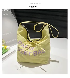 Detailed top view of a yellow tote bag with purple Paris embroidery and a decorative bow