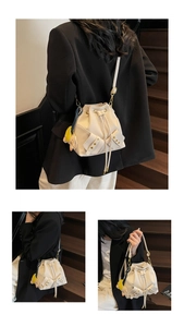Close-up of beige drawstring bucket bag featuring cute elephant charm and flap pockets