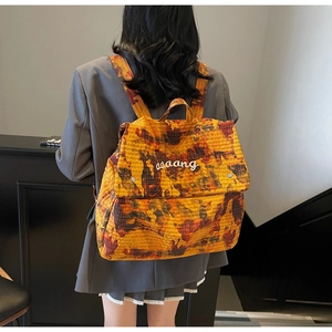 Detail view of the orange camouflage backpack with white embroidered logo on the flap