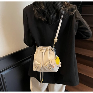 Detail of white pebbled leather bucket bag featuring drawstring closure and elephant charm
