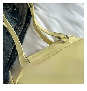 Close-up of the yellow patent leather handbag strap with detailed stitching and metal buckle