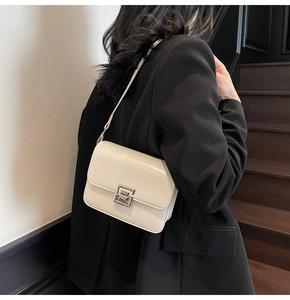 Detail of cream white leather crossbody bag with silver geometric buckle on black blazer