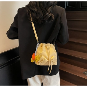 Detail of cream bucket bag with drawstring closure and orange elephant charm accessory