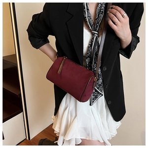 Close-up of wine red suede barrel crossbody bag with dark brown leather shoulder strap