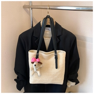 Detail of hand-woven beige tote bag with black leather straps and a cute puppy charm