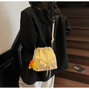 Detail of light yellow bucket bag with drawstring closure and orange elephant charm