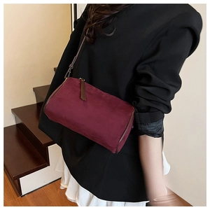 Detail view of burgundy suede crossbody bag showing the texture and thin shoulder strap