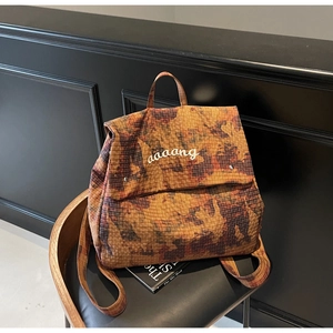 Close-up of camouflage print backpack with grid texture and white letter logo detail