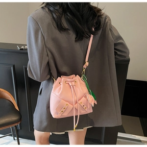 Pink drawstring bucket bag with litchi texture and cute pig charm accessory detail