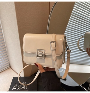 Detail shot of the cream crossbody square bag with a silver geometric buckle and glossy finish