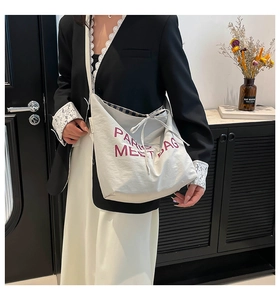 Detail of cream tote bag featuring purple Paris embroidery and drawstring bow handles
