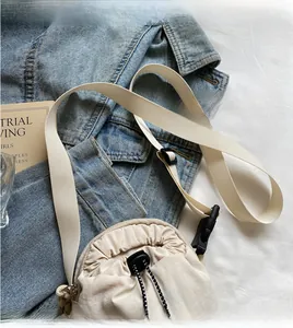 Detail of beige drawstring crossbody bag with adjustable wide shoulder strap and cord lock
