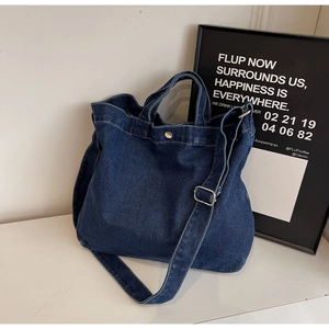 Close-up of dark denim tote bag featuring silver snap button and adjustable shoulder strap