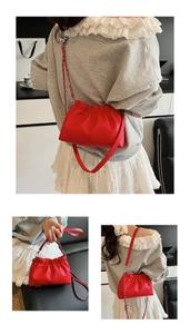 Detail of red ruched shoulder bag with grainy leather texture and silver chain strap