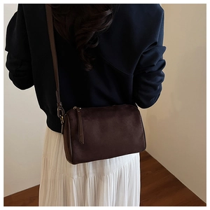 Detail of suede Boston bag in dark brown worn by model with adjustable shoulder strap