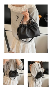 Detail view of black pleated bucket bag with chain strap and adjustable leather strap