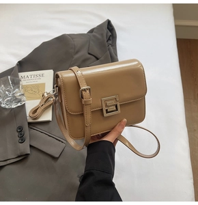 Detail of camel leather crossbody bag with silver metal lock and adjustable strap