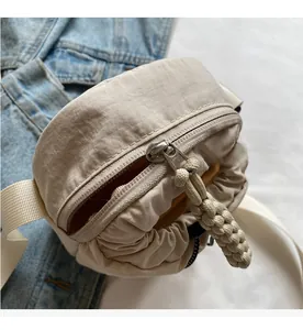 Close-up of beige nylon crossbody bag with smooth zipper and yellow lining detail