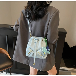 Detail view of light blue leather bucket bag with drawstring and elephant charm