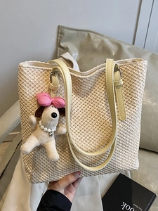 Handmade straw tote bag with leather straps and cute puppy pendant on beige surface