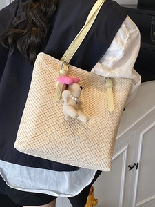 Handmade woven straw tote bag with yellow leather straps and a plush dog charm
