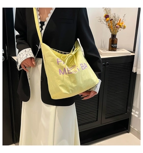 Detail of a bright yellow crossbody bag featuring purple embroidery and drawstring closure