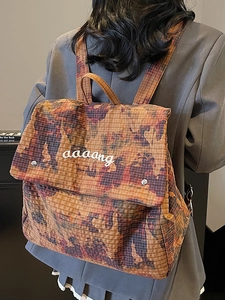 Water-dyed camo backpack in orange-brown grid fabric worn by model for daily commute