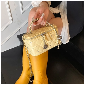 Macro shot of yellow quilted PU leather with crystal studs and golden chain handle detail