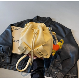 Detail of light yellow leather bucket bag with drawstring closure and elephant charm