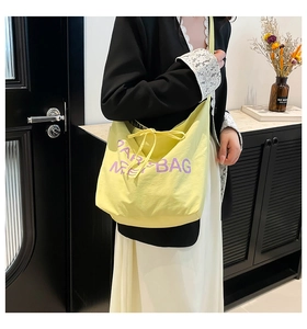 Detail view of light yellow tote bag with purple PARIS MEET BAG embroidery and bow