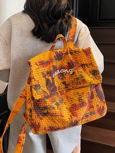 Orange camouflage nylon backpack with flap closure and adjustable straps in casual scene