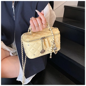 Close-up of a yellow quilted crossbody bag with sparkling rhinestones and chain strap