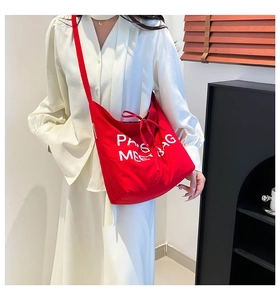 Detail of red canvas tote bag showing wide shoulder strap and PARIS MEET BAG lettering