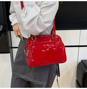 Detail of red glossy oil wax leather handbag with dual zippers and silver metal rings