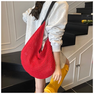 Detailed close-up of vibrant red woven hobo bag with contrast black shoulder strap