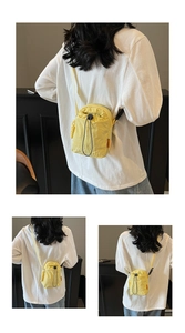 Detail of a bright yellow nylon drawstring crossbody bag with white brand logo print