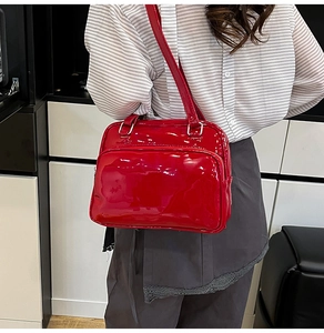 Detail view of red glossy oil-wax leather shoulder bag showing the zipper pocket and finish