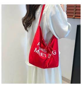 Detail of red canvas tote bag with white Paris Meet Bag text and side bow accent