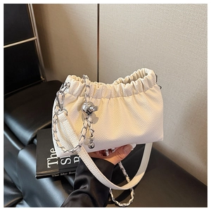 Detail of white lychee leather texture and silver spherical metal buckle on shoulder bag