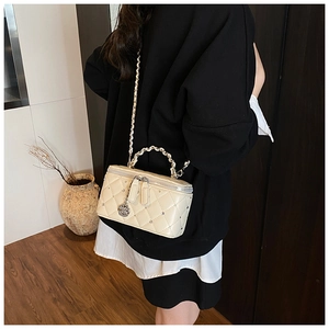 Detail view of cream quilted chain bag with camellia pendants and pearl handle