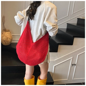 Detailed back view of a red hand-woven hollow-out tote bag in a minimalist setting