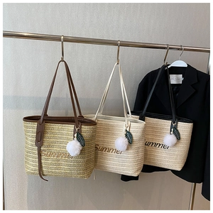 Detailed view of woven straw tote bags with Summer embroidery and tassel charms