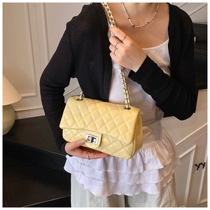 Detail of quilted leather texture and metal turn-lock closure on yellow chain bag